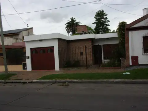 CASA DE CUATRO AMBIENTES EN UNA PLANTA CON FONDO VERDE Y QUINCHO.